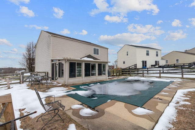 snow covered pool with a diving board and a sunroom