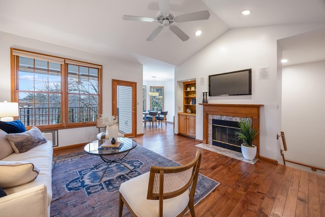 living room featuring ceiling fan, hardwood / wood-style flooring, a fireplace, and built in shelves