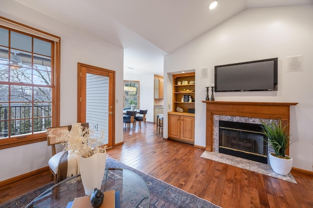 living room featuring a premium fireplace, built in shelves, high vaulted ceiling, and light hardwood / wood-style flooring