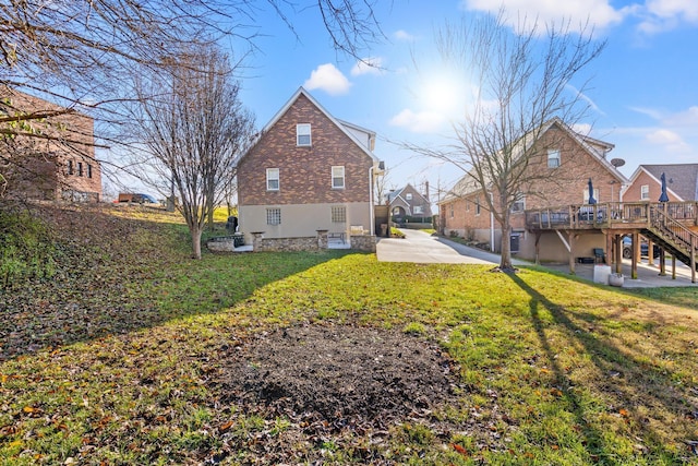 view of side of home with a wooden deck, a patio, and a lawn