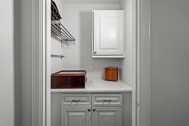 bar with tasteful backsplash and white cabinets