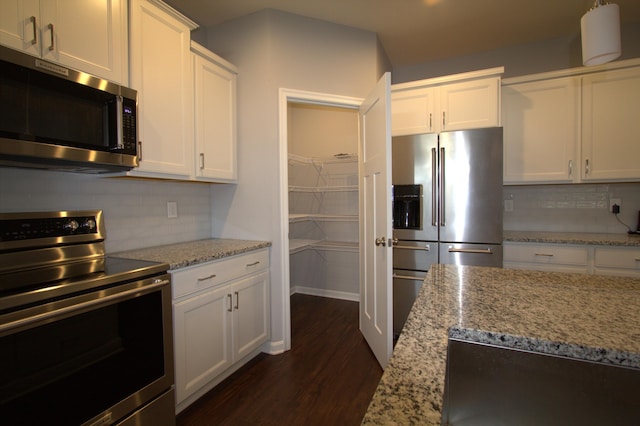 kitchen featuring dark wood finished floors, white cabinetry, stainless steel appliances, and tasteful backsplash