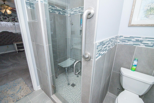 bathroom with tile walls, an enclosed shower, ceiling fan, toilet, and tile patterned floors