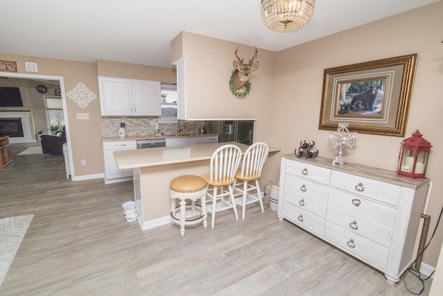 kitchen featuring white cabinetry, a breakfast bar, light hardwood / wood-style floors, and kitchen peninsula