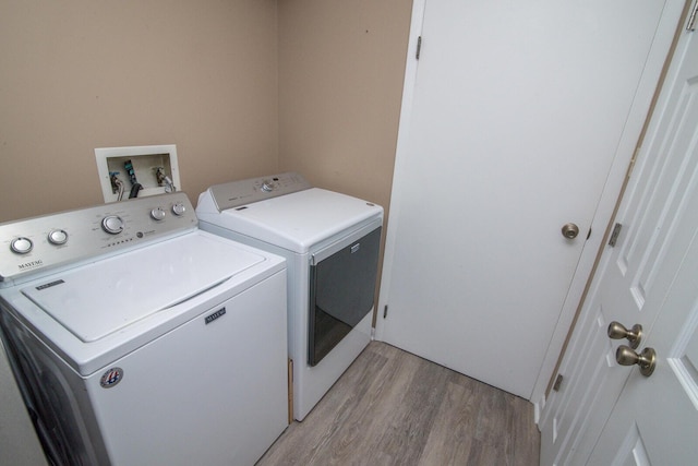 clothes washing area with washing machine and clothes dryer and light hardwood / wood-style floors