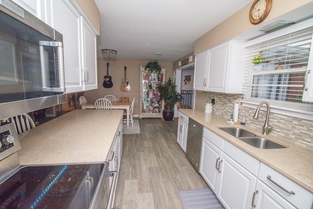 kitchen with white cabinetry, stainless steel appliances, sink, and light hardwood / wood-style flooring