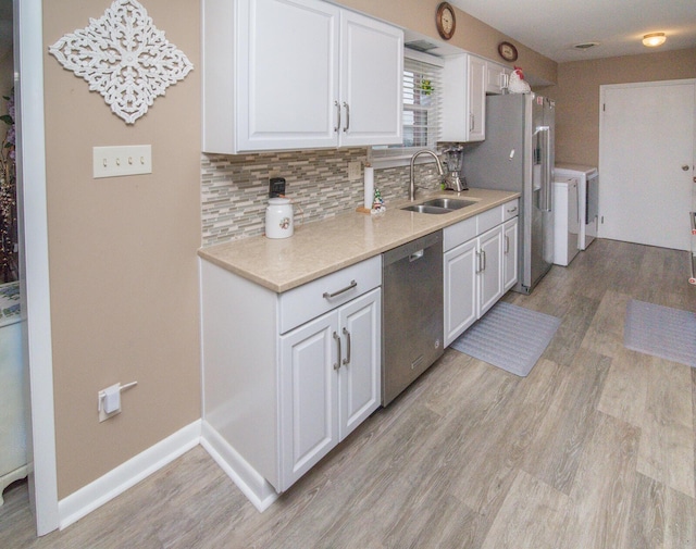 kitchen with stainless steel appliances, white cabinetry, sink, and tasteful backsplash