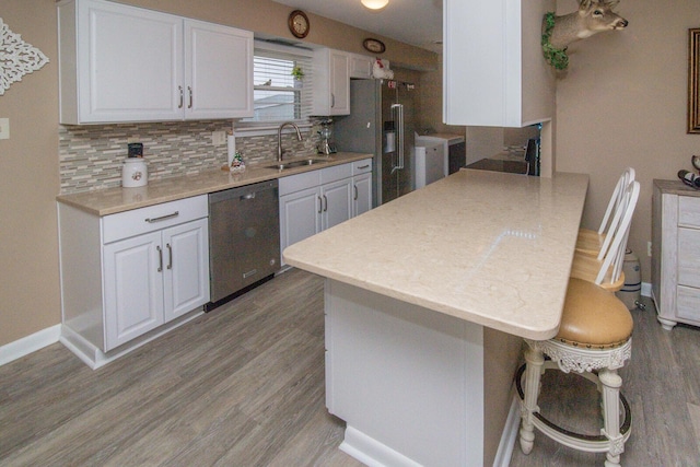 kitchen featuring sink, backsplash, white cabinets, a kitchen breakfast bar, and stainless steel appliances