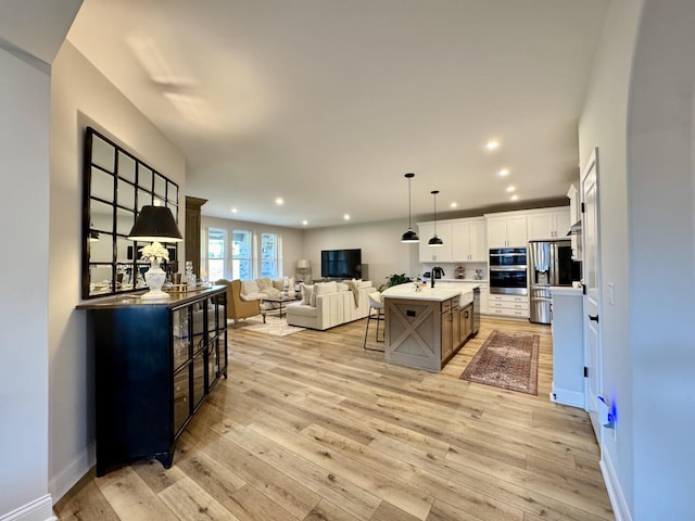 1516 Brumfield Ct, Union, KY 41091 - kitchen featuring appliances with stainless steel finishes, open floor plan, recessed lighting, a kitchen breakfast bar, and light wood finished floors