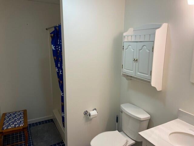 bathroom featuring vanity, tile patterned flooring, curtained shower, and toilet