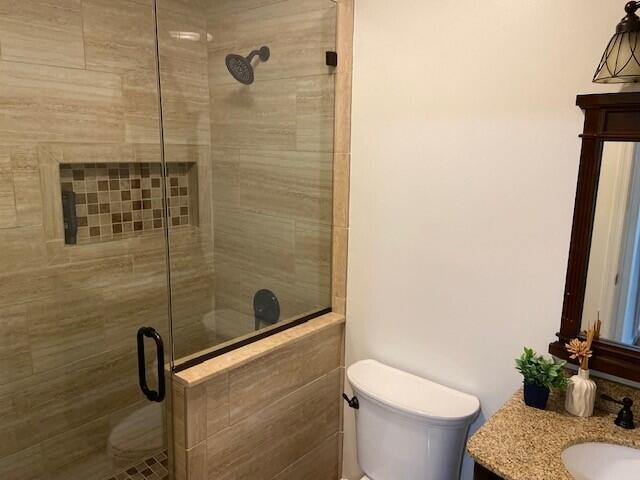 bathroom featuring an enclosed shower, vanity, and toilet