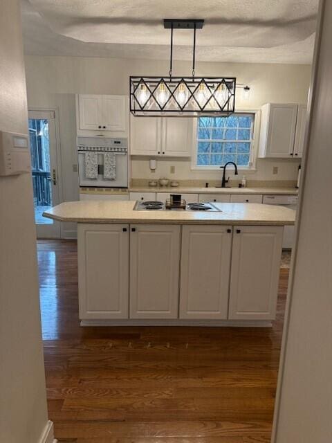 kitchen with decorative light fixtures, dark hardwood / wood-style floors, a kitchen island, white appliances, and white cabinets