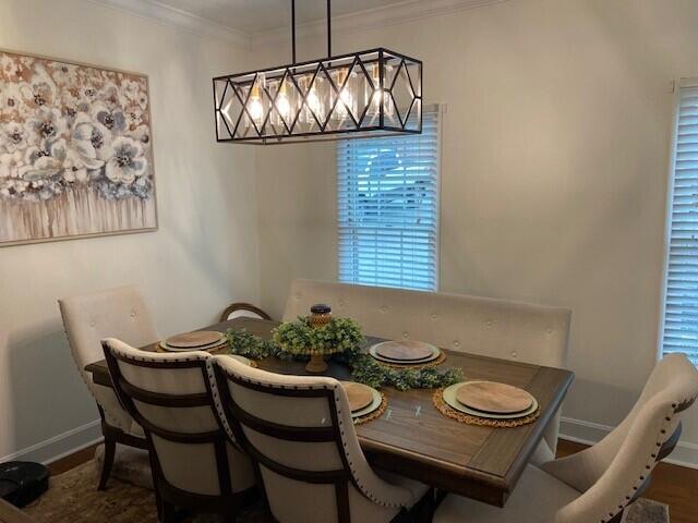 dining area featuring ornamental molding, a notable chandelier, and dark hardwood / wood-style flooring