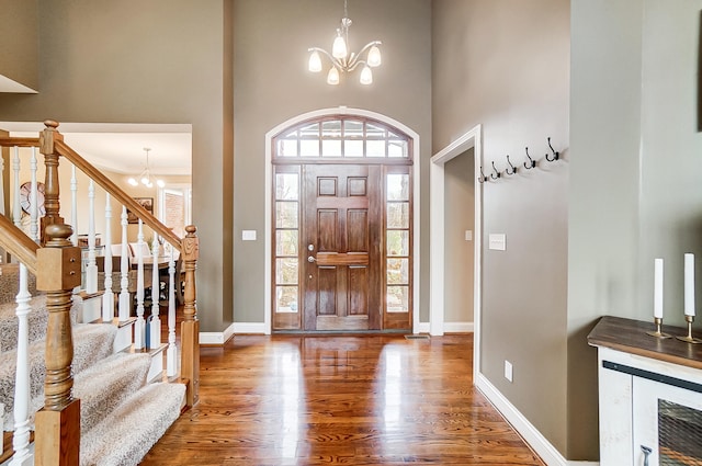 foyer entrance featuring wood-type flooring, a chandelier, and a high ceiling