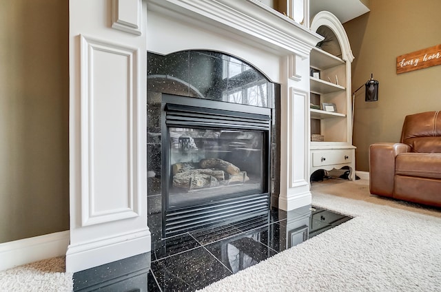 interior details featuring a tiled fireplace and carpet floors