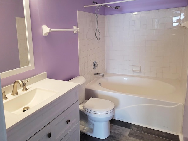 full bathroom featuring hardwood / wood-style flooring, tiled shower / bath, vanity, and toilet