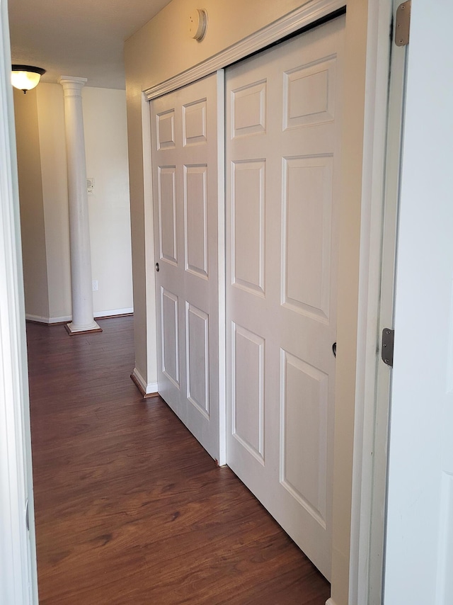 hallway featuring dark wood-type flooring and ornate columns