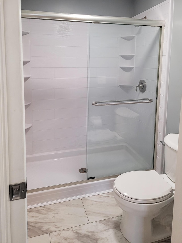 bathroom featuring a shower with shower door and toilet