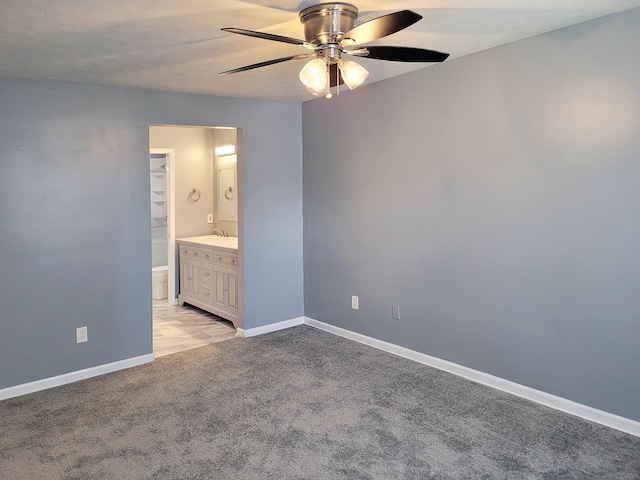 unfurnished bedroom with ceiling fan, light colored carpet, connected bathroom, and sink