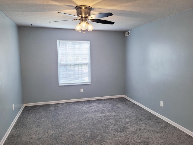 unfurnished room with ceiling fan, dark carpet, and a textured ceiling