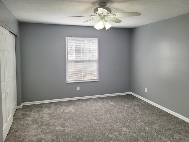 unfurnished room featuring ceiling fan and dark colored carpet