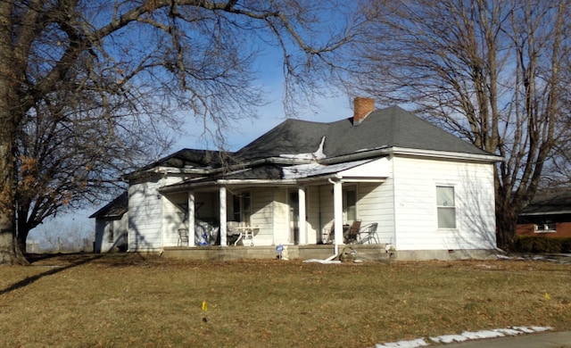 view of front of home with roof with shingles, a porch, a front lawn, and a chimney