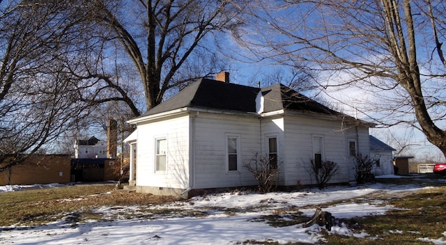 view of snow covered exterior featuring a chimney and roof with shingles