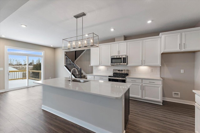 kitchen with stainless steel appliances, light countertops, a sink, and a center island with sink