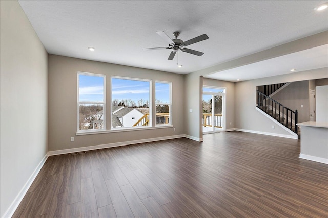 unfurnished living room featuring baseboards, stairway, and dark wood finished floors