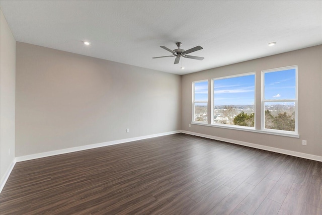 empty room featuring a ceiling fan, recessed lighting, dark wood finished floors, and baseboards