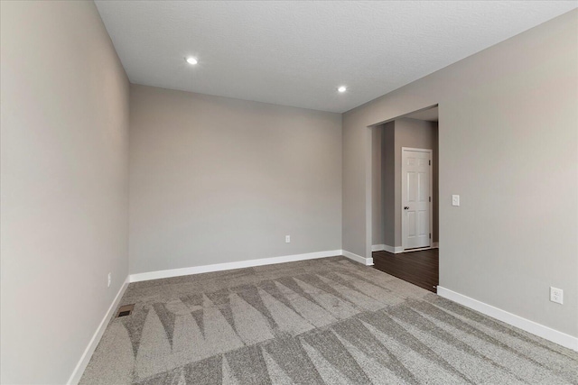 carpeted spare room featuring baseboards, visible vents, a textured ceiling, and recessed lighting