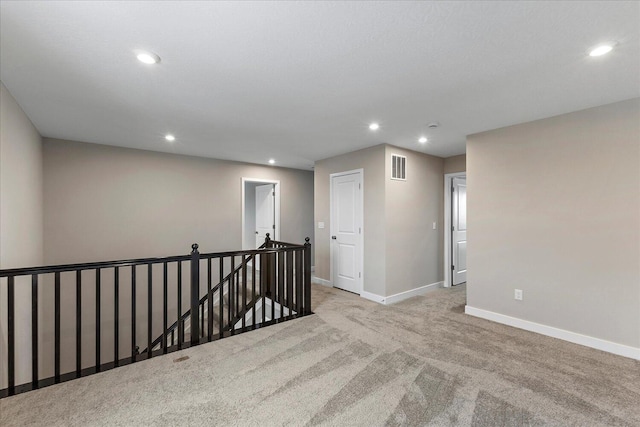 empty room with light carpet, recessed lighting, visible vents, and baseboards