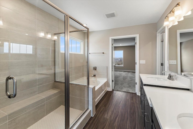 bathroom featuring a garden tub, wood finished floors, a sink, visible vents, and a stall shower