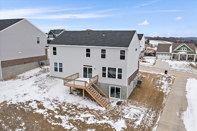 snow covered property featuring a deck, stairway, and a residential view