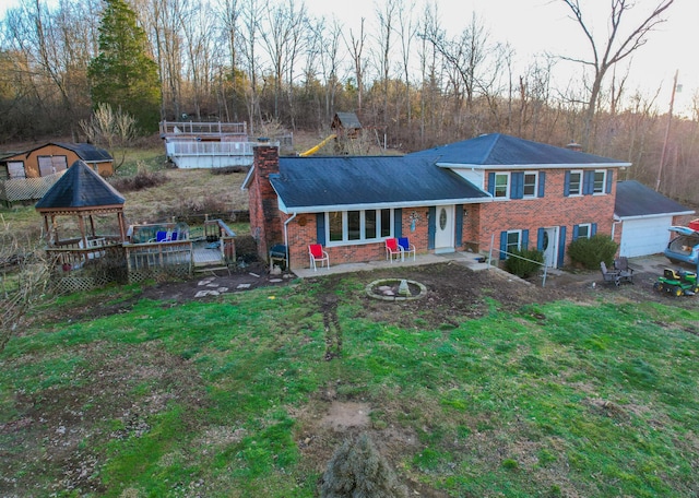 view of front of home with a gazebo, an outdoor fire pit, a wooden deck, a garage, and a front lawn