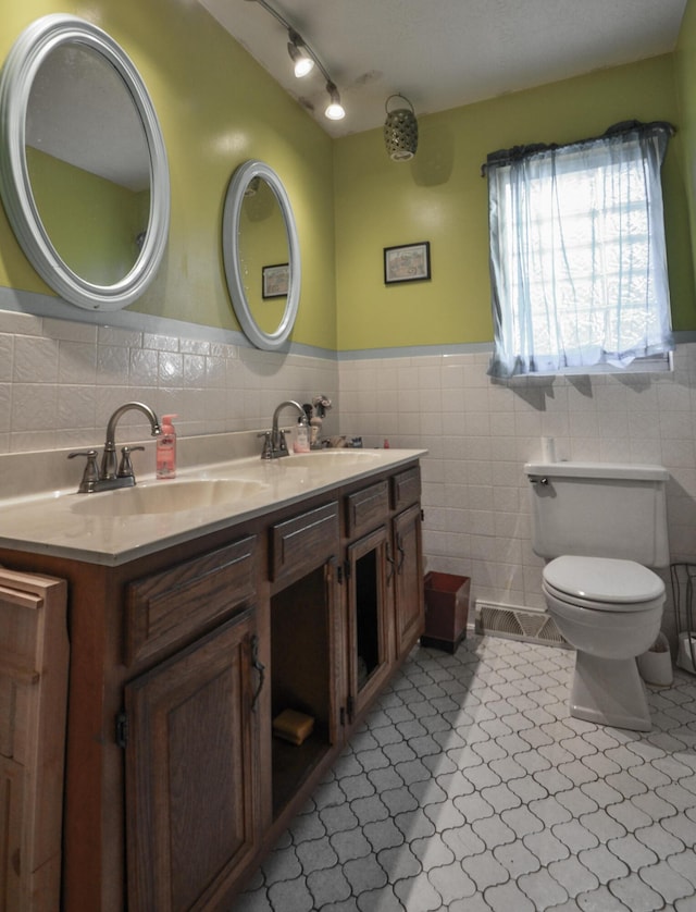 bathroom with vanity, tile patterned flooring, tile walls, and toilet