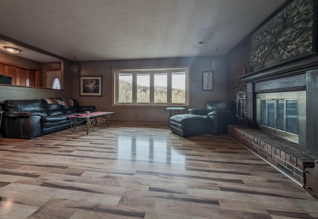 living room featuring a fireplace, light hardwood / wood-style flooring, and a textured ceiling