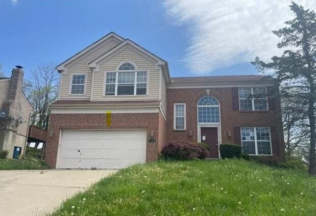 view of front of home featuring brick siding, an attached garage, driveway, and a front yard