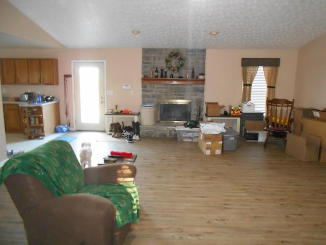 living room with plenty of natural light, a fireplace, a textured ceiling, and light wood-type flooring