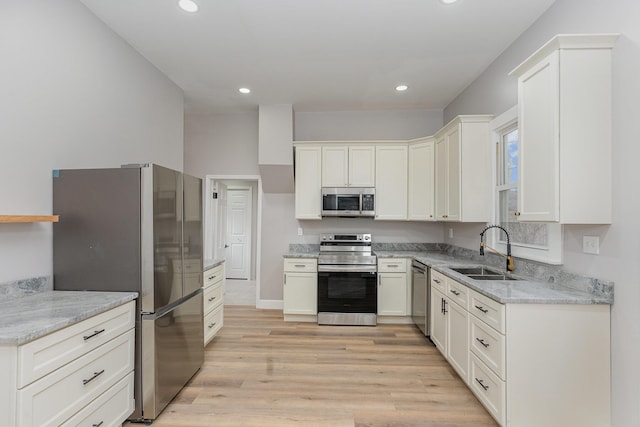 kitchen featuring light stone counters, sink, light hardwood / wood-style flooring, and stainless steel appliances