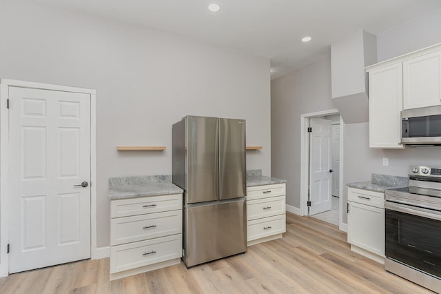 kitchen with light stone countertops, white cabinetry, appliances with stainless steel finishes, and light wood-type flooring