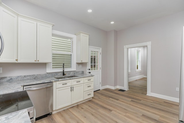 kitchen with stainless steel appliances, white cabinetry, sink, and light hardwood / wood-style floors