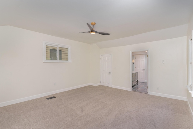 unfurnished bedroom with vaulted ceiling, light carpet, ceiling fan, and ensuite bath