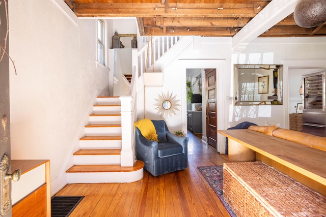 staircase featuring beamed ceiling and hardwood / wood-style floors