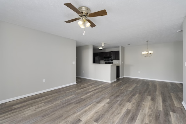 unfurnished living room with dark hardwood / wood-style flooring, ceiling fan with notable chandelier, and a textured ceiling