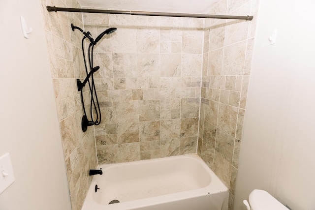 bathroom with tiled shower / bath combo and toilet