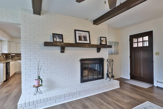 living room featuring hardwood / wood-style floors, ceiling fan, beamed ceiling, and a brick fireplace