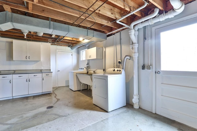 clothes washing area featuring cabinets, sink, and washer and dryer