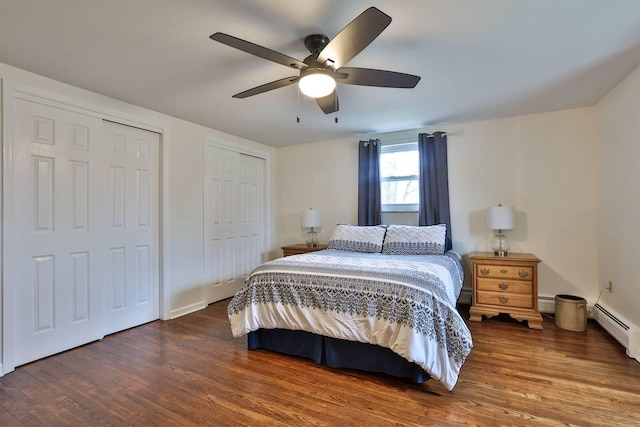 bedroom featuring ceiling fan, a baseboard heating unit, two closets, and dark hardwood / wood-style flooring