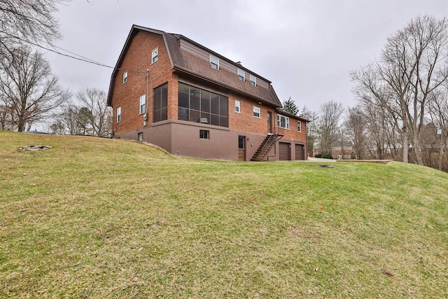 rear view of property featuring a yard, a garage, and a sunroom